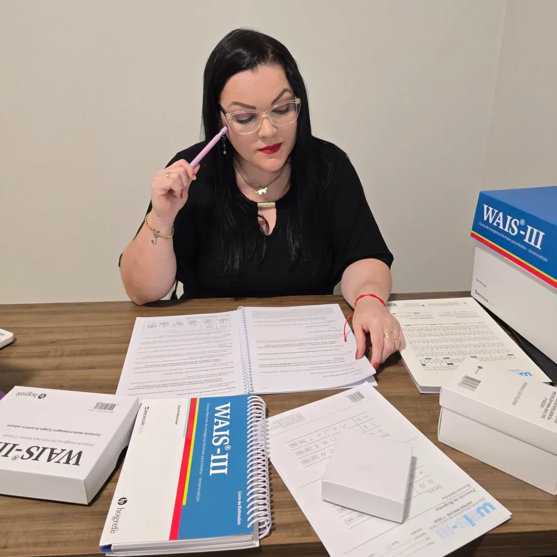 Janaína Catolino analisando testes psicológicos em sua mesa de trabalho